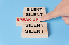 A finger pointing at a wooden block with the word 