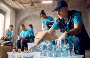 Mature volunteer organizing donations in boxes while working at humanitarian aid center.