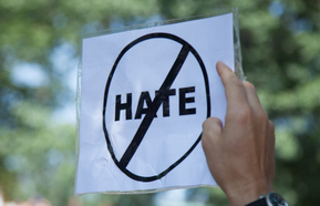 A person holds up a 'no hate' sign
