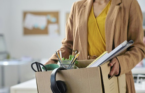 Close-up of businesswoman packing things in box while moving in new office