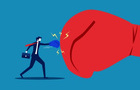 A small businessman punching against a big boxing glove
