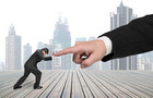 Small man pushing against a big index finger