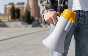Close-up protester with megaphone for demonstration, man wears jeans and shirt