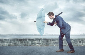 A man with an umbrella pushing against the wind.