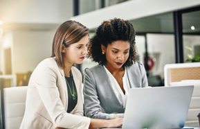 Business women planning in corporate office, using a computer.