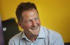 Jon Sparkes, chief executive of Mencap, smiling in front of a yellow background