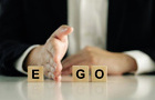 A person puts their hand between wooden blocks with the words Ego and GO