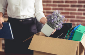 Picture of staff member with carboard box filled with items from an office.