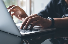 Fingers typing on a laptop computer
