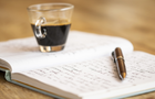 A coffee cup, notepad and pen