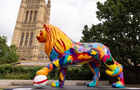 A multi-coloured lion sculpture in front of the Houses of Parliament.