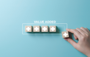 Value add concept. Hand places wooden cube with plus sign on light blue background