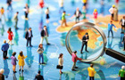 A group of miniature people under a magnifying glass 